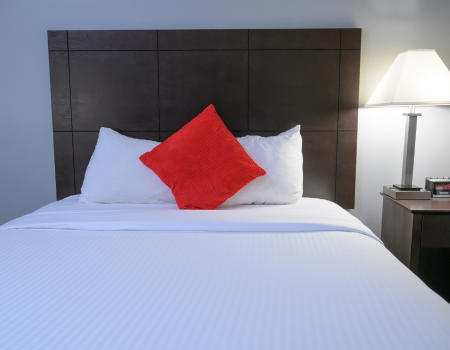 bed in guest room with red pillow