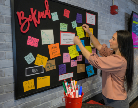 girl putting kindness note on wall