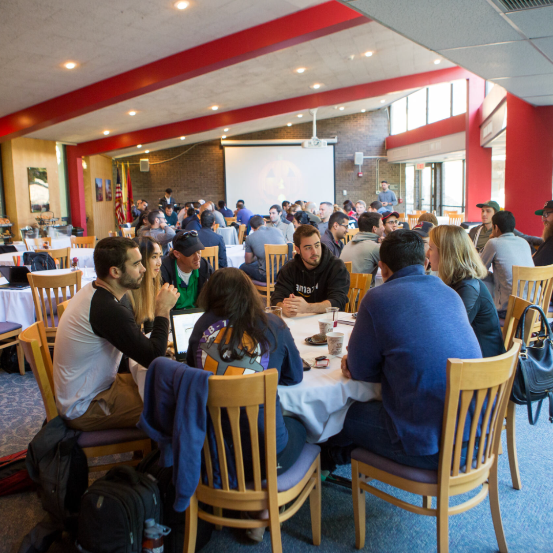 meeting hosted in sun-lit dining room with people sitting at tables and chairs talking