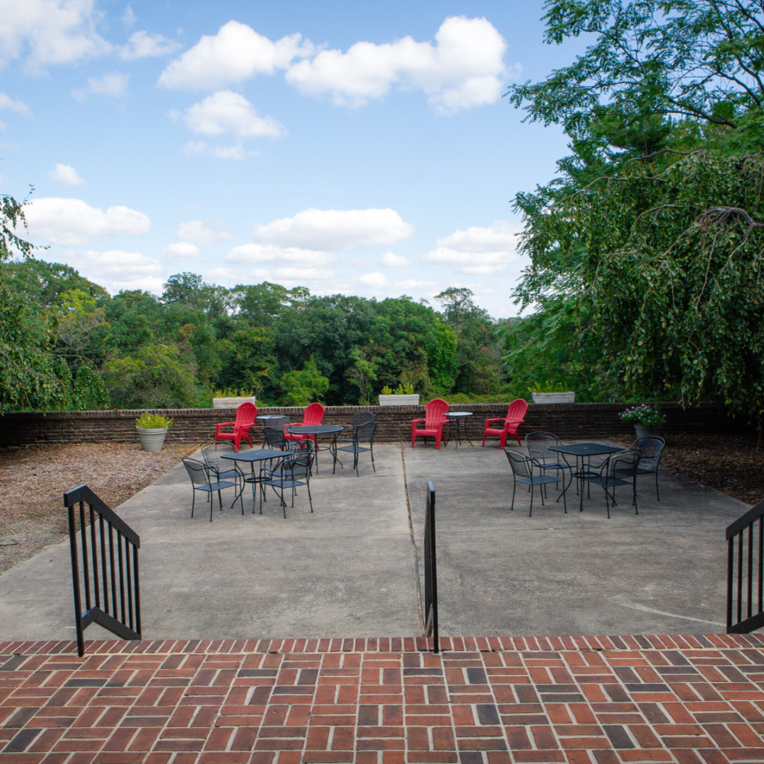 outdoor photo of the view from the back patio with red and black tables and chairs