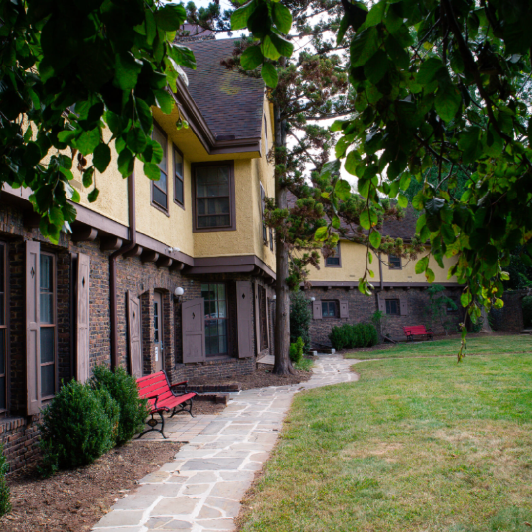 artsy outdoor image of the front of the inn from a side view under tree leaves